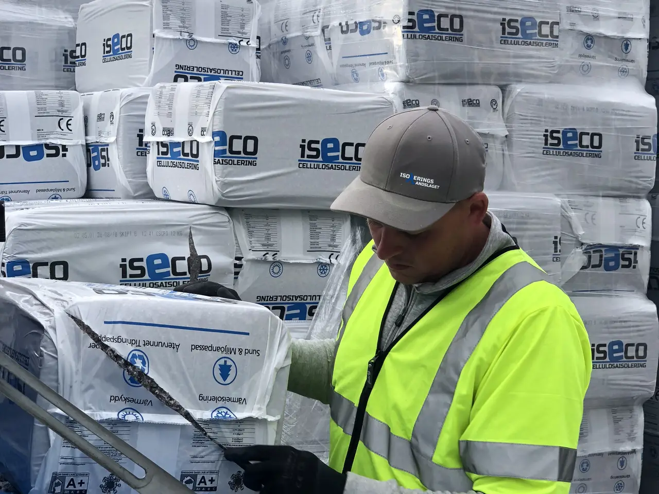 Installatör vid staplade balar med isolering på en byggarbetsplats